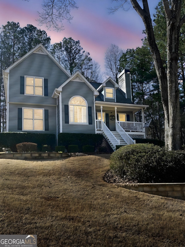 view of front of property with a chimney, a porch, and a front yard