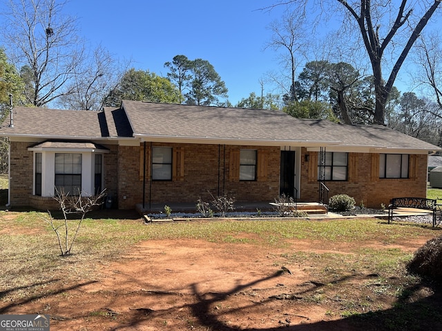 ranch-style house featuring brick siding, a shingled roof, and a front yard