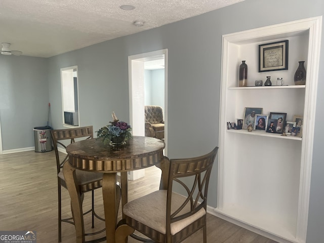 dining room featuring a textured ceiling, baseboards, and wood finished floors