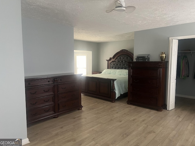 bedroom featuring a closet, a spacious closet, light wood finished floors, and a textured ceiling