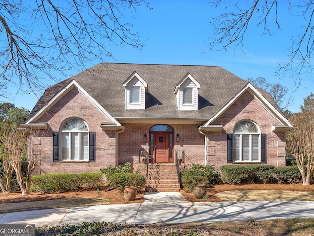 view of front facade with brick siding and roof with shingles