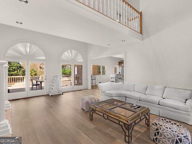 living area with recessed lighting, decorative columns, a towering ceiling, and wood finished floors