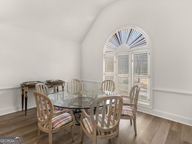 dining space featuring lofted ceiling, wood finished floors, and baseboards