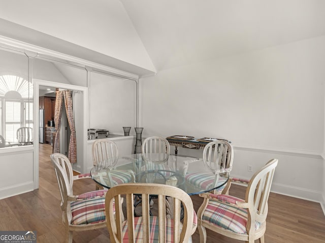 dining room with vaulted ceiling, wood finished floors, and baseboards