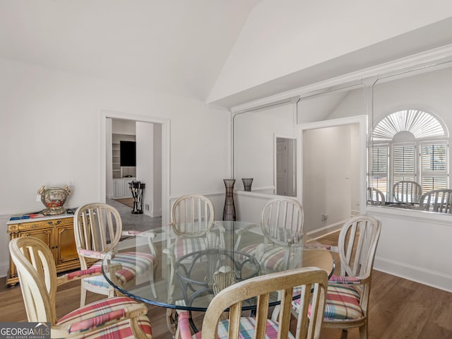 dining space with vaulted ceiling, wood finished floors, and baseboards