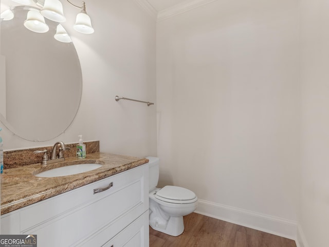 bathroom featuring crown molding, toilet, vanity, wood finished floors, and baseboards