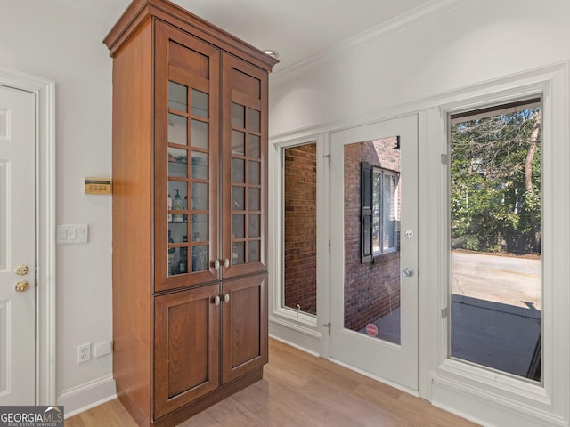 entryway featuring baseboards, french doors, light wood-style flooring, and crown molding