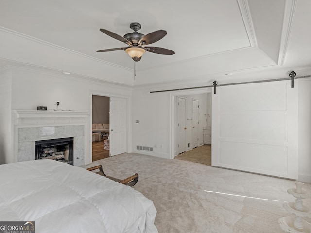 bedroom featuring a barn door, visible vents, a raised ceiling, and crown molding