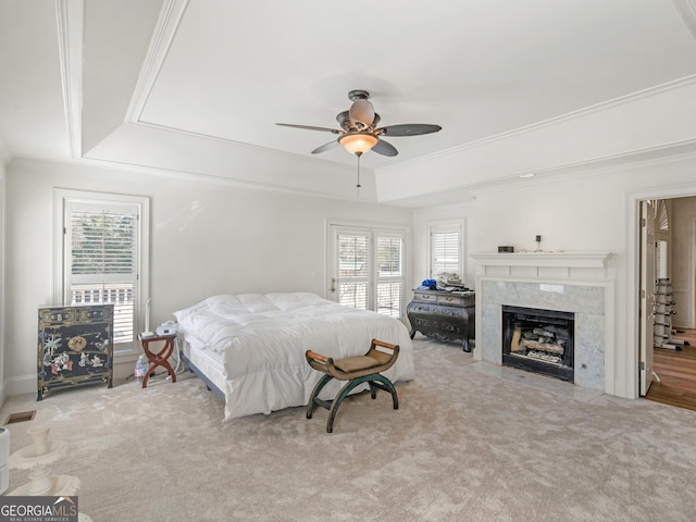 bedroom with carpet floors, multiple windows, ornamental molding, and a raised ceiling