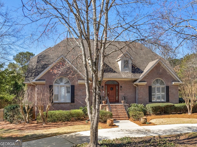 view of front facade featuring brick siding and a shingled roof