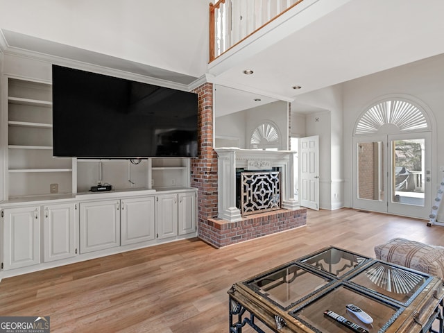 living room with recessed lighting, a fireplace, light wood-style flooring, and a towering ceiling