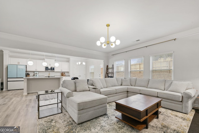 living room with ornamental molding, light wood-type flooring, visible vents, and a notable chandelier