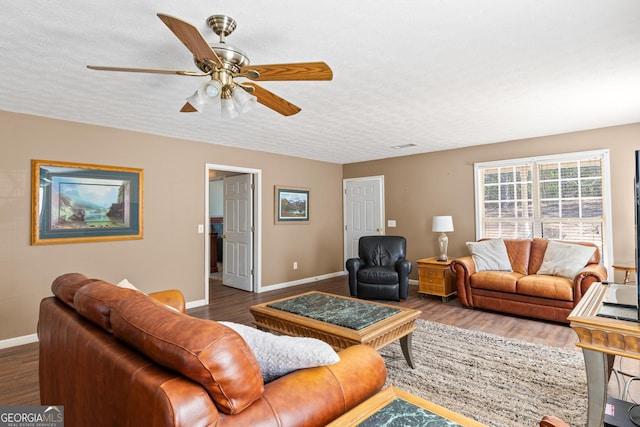 living area featuring a textured ceiling, baseboards, and wood finished floors