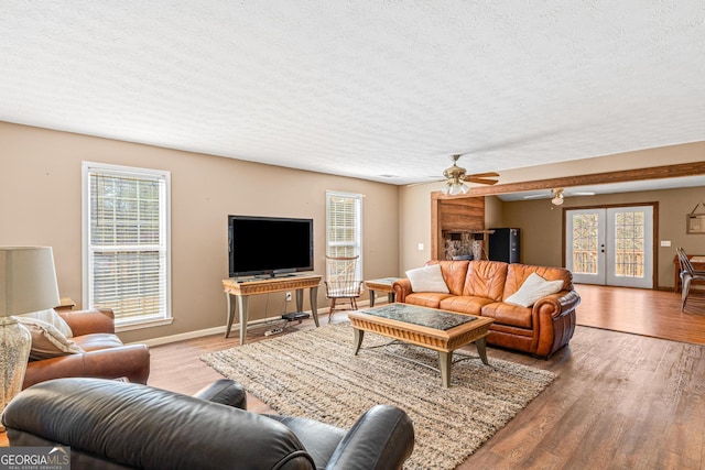 living room featuring a textured ceiling, baseboards, wood finished floors, and french doors