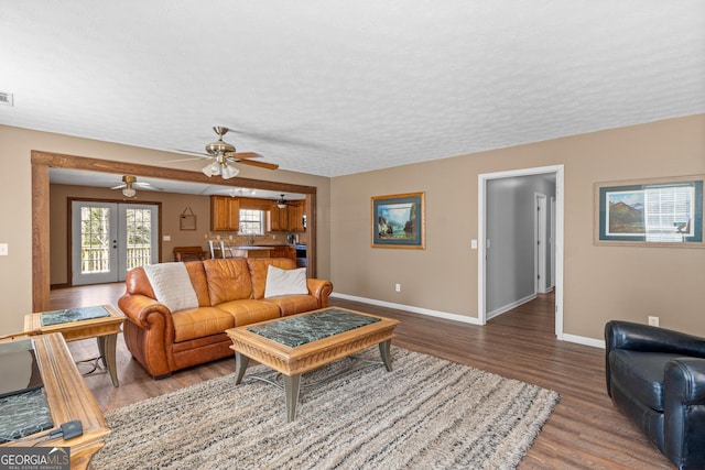 living area with french doors, visible vents, a textured ceiling, wood finished floors, and baseboards