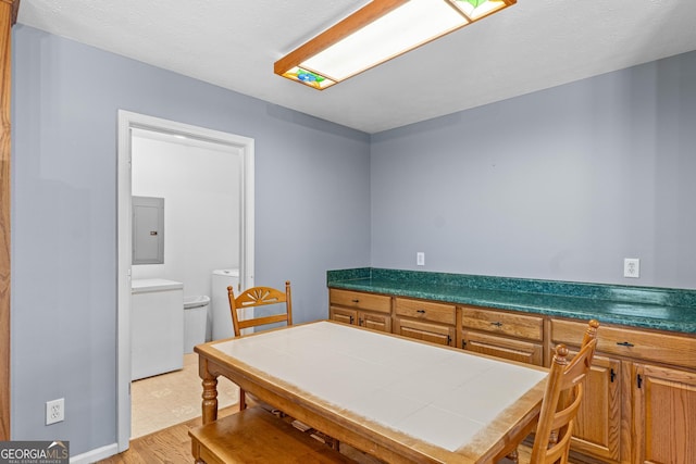 interior space with light wood-type flooring, electric panel, tile countertops, and washing machine and clothes dryer