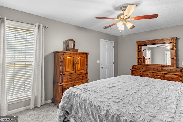 bedroom with a textured ceiling, baseboards, a ceiling fan, and light colored carpet