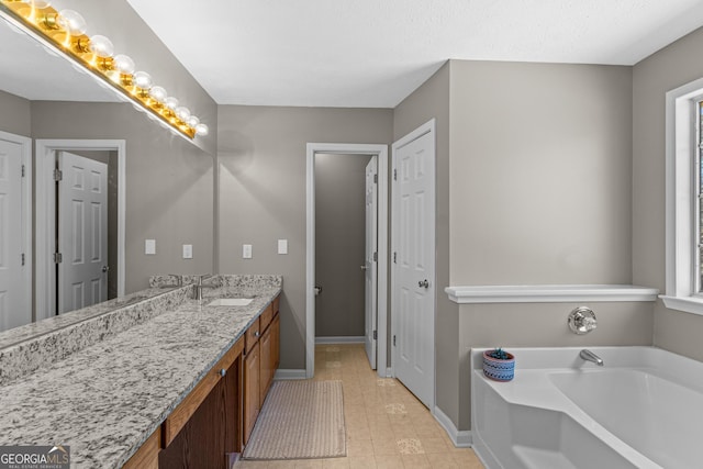 bathroom with a garden tub, baseboards, and vanity