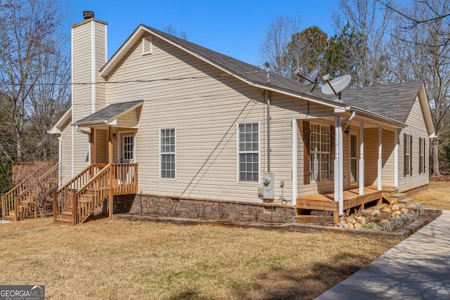 exterior space featuring covered porch, a lawn, and a chimney