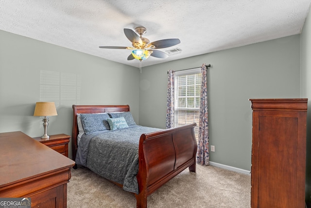 bedroom featuring light colored carpet, visible vents, ceiling fan, a textured ceiling, and baseboards