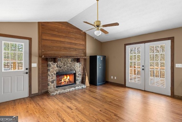 unfurnished living room featuring a fireplace, wood finished floors, a ceiling fan, vaulted ceiling, and french doors