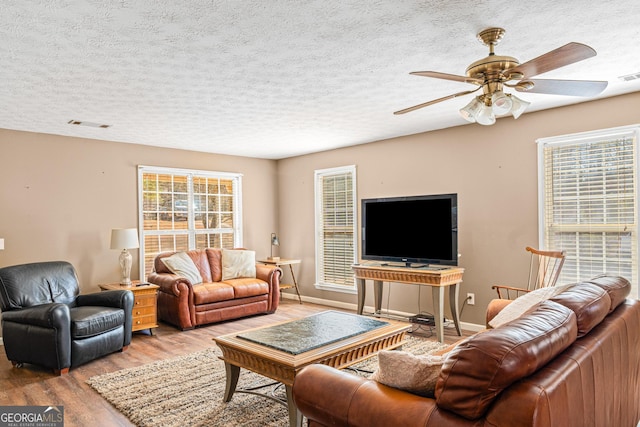 living area featuring light wood finished floors, baseboards, and a textured ceiling