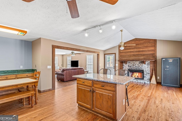 kitchen with vaulted ceiling, light wood-type flooring, open floor plan, and a fireplace