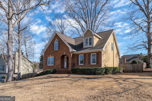 view of front of house with a shingled roof, a gate, brick siding, and fence