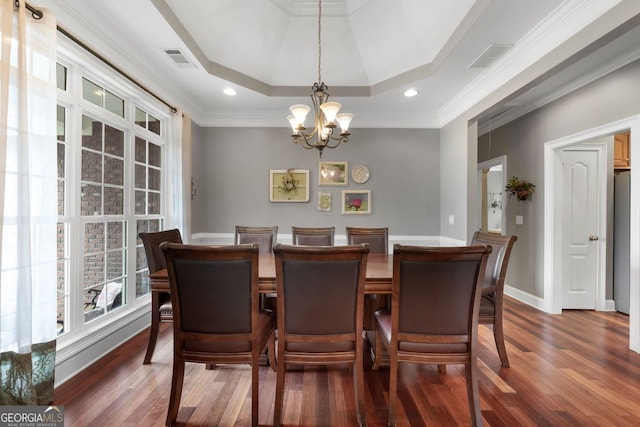 dining area featuring an inviting chandelier, visible vents, a raised ceiling, and wood finished floors