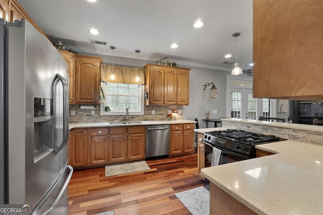 kitchen featuring visible vents, ornamental molding, a sink, stainless steel appliances, and backsplash