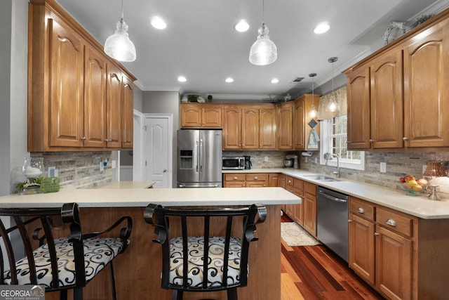 kitchen featuring a breakfast bar, stainless steel appliances, ornamental molding, a sink, and a peninsula