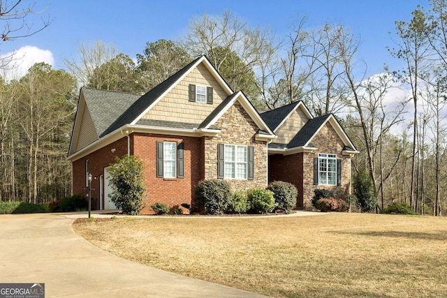 craftsman-style home featuring driveway, stone siding, brick siding, and a front yard