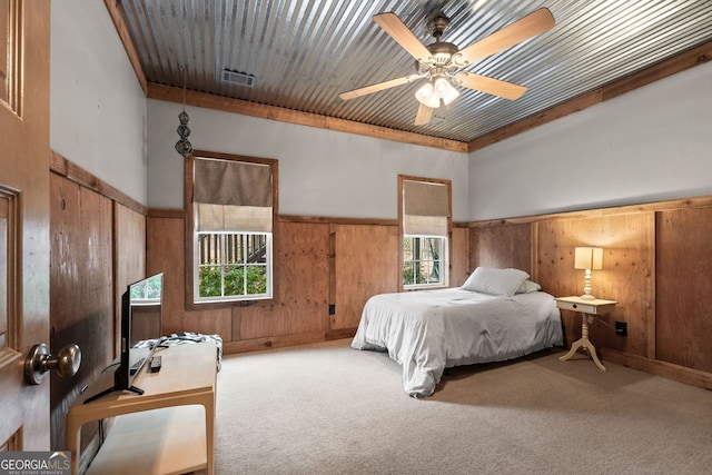 carpeted bedroom featuring wooden walls, a wainscoted wall, wood ceiling, a ceiling fan, and visible vents