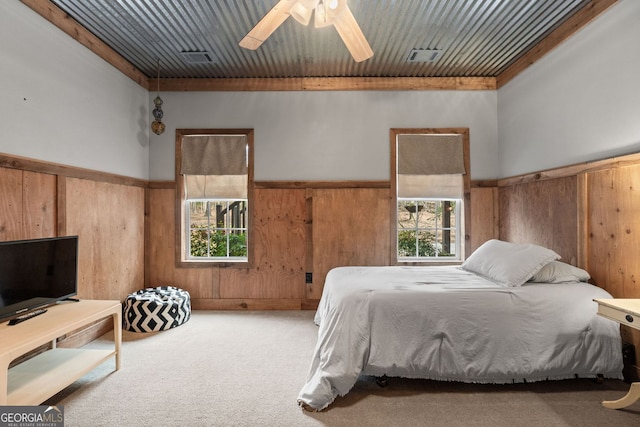 bedroom with ceiling fan, a wainscoted wall, wood walls, visible vents, and carpet