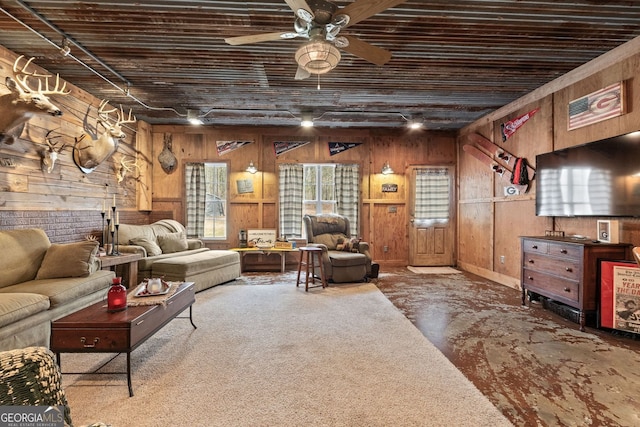 living area with ceiling fan and wooden walls