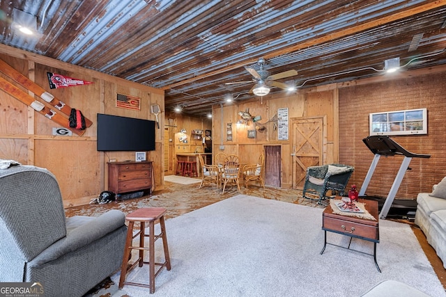 living area with a ceiling fan, wooden ceiling, and wooden walls