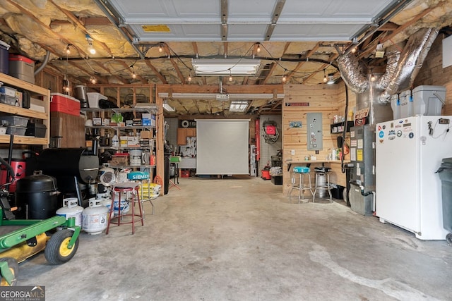 garage featuring freestanding refrigerator, a workshop area, and electric panel