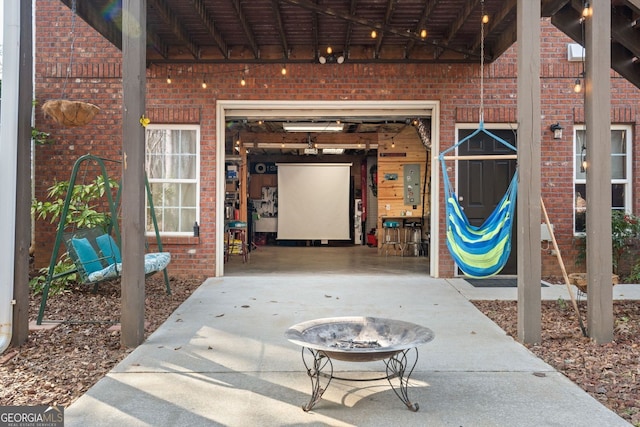 doorway to property featuring a garage, electric panel, concrete driveway, and brick siding