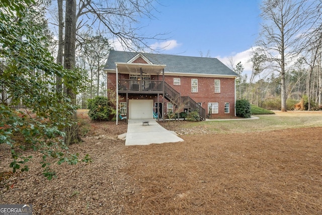 rear view of house featuring a lawn, ceiling fan, an attached garage, stairs, and brick siding