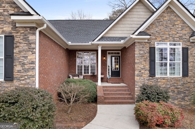 entrance to property featuring stone siding, brick siding, and roof with shingles