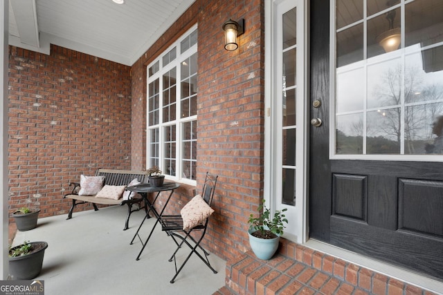 property entrance featuring a porch and brick siding