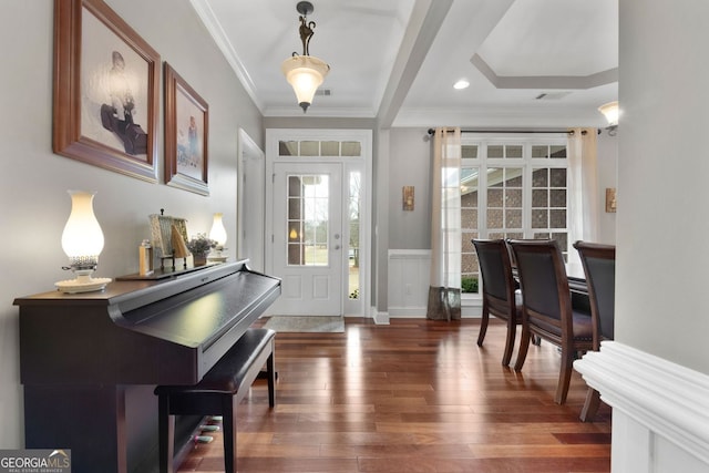 foyer entrance with wainscoting, wood finished floors, visible vents, and crown molding