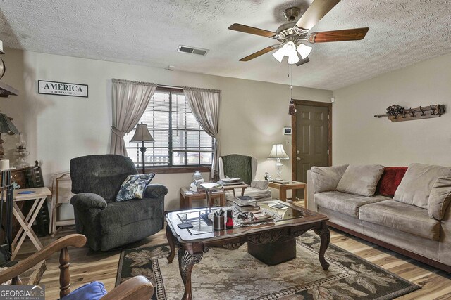 living room with visible vents, ceiling fan, a textured ceiling, and wood finished floors