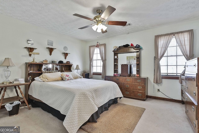 bedroom featuring ceiling fan, a textured ceiling, light carpet, visible vents, and baseboards