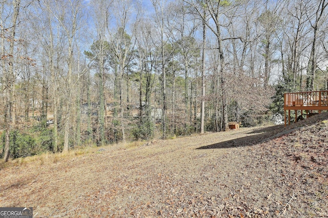 view of yard featuring a forest view and a wooden deck