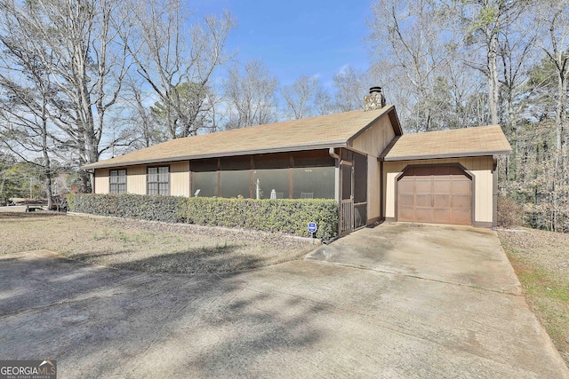 view of side of home with a garage, driveway, and a chimney