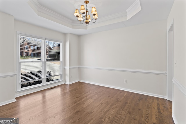 spare room featuring baseboards, a raised ceiling, wood finished floors, crown molding, and a notable chandelier