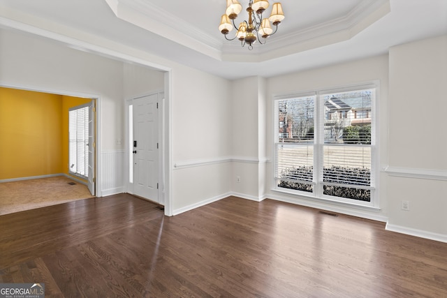 interior space with a tray ceiling, visible vents, ornamental molding, wood finished floors, and a chandelier