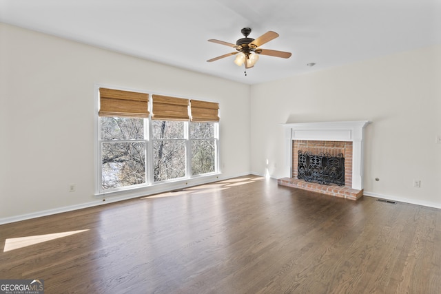 unfurnished living room with a brick fireplace, baseboards, and wood finished floors