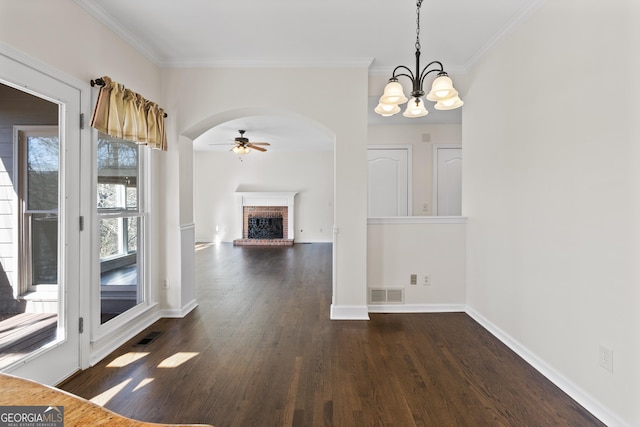 unfurnished dining area with dark wood-style floors, arched walkways, a brick fireplace, and visible vents